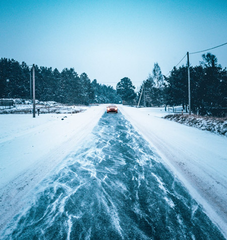 Professionals applying ice control treatments in a snowy area, demonstrating effective management of icy conditions for enhanced pedestrian and vehicle safety.